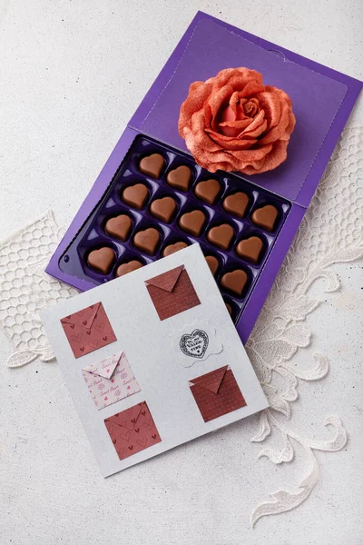 stock image Violet box of heart shaped chocolates, postcard and fabric rose flower on white background. Valentines day 14 February sweet present