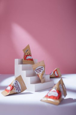 İzmail, Ukrayna. Mayıs 2022. Gece maskeli balkabağı uyku tulumları beyaz masada küçük paketlerde sert gölgelerde, pembe arka planda. Bakım kozmetikleri