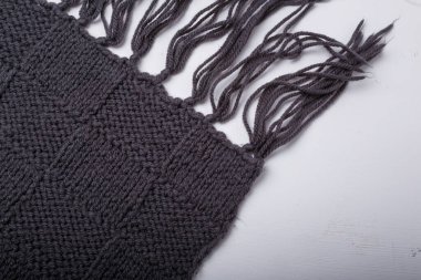 Dama desenli gri örgü eşarp ve beyaz arka planda iplik püskülleri, yakın çekim