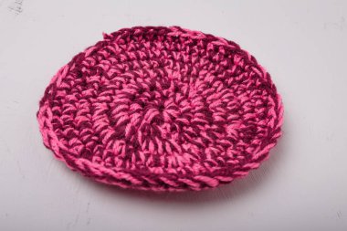 Beyaz arka planda sıcak fincanlar için yuvarlak örülmüş melanj pembe paspas, yakın plan çekim