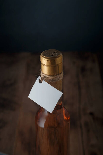 Upper part of 250 ml bottle of pink wine with blank label. Alcohol drink on dark blue wooden background. Close up, copy space