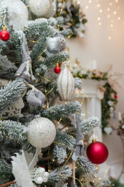 Noel ağacı yapay kar ve dekore edilmiş şömine arka planında ampullerle kaplı. Mutlu yıllar için ağaç dalları ve oyuncaklar