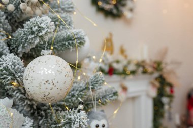 Noel ağacı yapay kar ve dekore edilmiş şömine arka planında ampullerle kaplı. Mutlu yıllar için ağaç dalları ve oyuncaklar