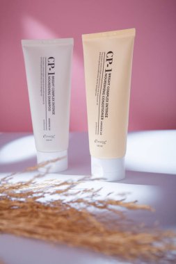 İzmail, Ukrayna. Mayıs 2022. Estetik, parlak, yoğun, besleyici saç kremi ve pembe arka planda şampuan, sert gölgeler.