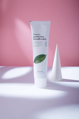 İzmail, Ukrayna. Mayıs 2022. Median Pleasia yeşil çay nefesi diş macunu doğal taze, beyaz masaya tüp, sert ışıkta pembe zemin