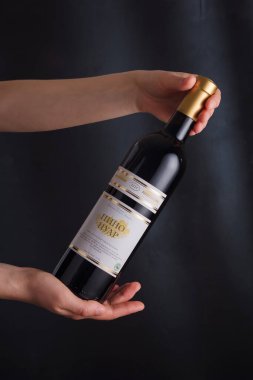 İzmail, Ukrayna. Kasım 2022. Siyah arka planda kırmızı şarap şişesi tutan eller. Bessarabia Şaraphanesi