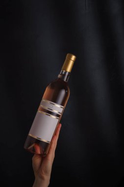 Elinde sahte etiketli pembe şarap şişesi, siyah arka planda markası yok. pinot noir. Alkol içeceği, kopyalama alanı