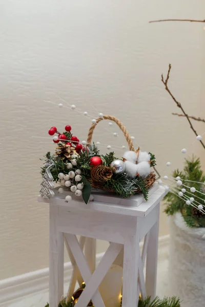 クリスマスの花構成 モミの枝からの花束 赤い果実と中キャンドルと提灯のバスケットの白い綿の花 — ストック写真