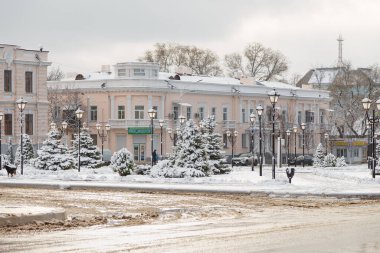 Beautiful winter cityscape: buildings, trees and street lamps covered with snow. Inscription on shop in Ukrainian - School child