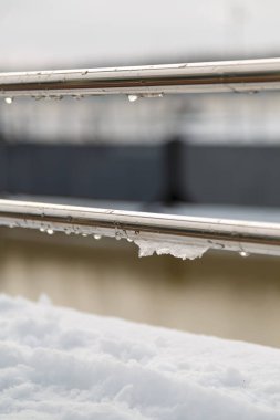 Tırabzan, su damlaları ve ıslak kar birikintisi. Erken bahar hava koşulları, eriyen kar ve erime