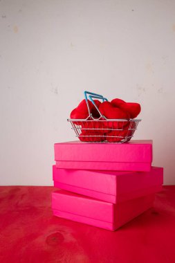 Kırmızı kalpli alışveriş sepeti yumuşak fuayeler, parlak arka planda kutular. Sevgililer günü indirimi, hediyeler. Kart kopyalama alanı