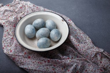 Paskalya yumurtaları gri ahşap arka planda mutfak havlusuyla maviye boyandı. Boşluğu kopyala