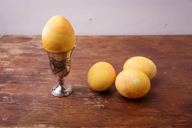 Sarı zerdeçal boyalı Paskalya yumurtası kırsal masada gümüş yumurta kabında. Mutlu Paskalyalar, bahar konsepti. Üst manzara, yakın çekim