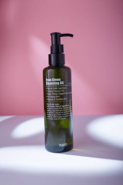 Izmail, Ukraine. May 2022. Purito from green cleansing oil for all skin types bottle on white table, pink backdrop