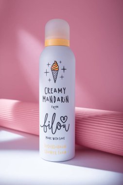 Izmail, Ukraine. May 2022. Shower foam Bilou Creamy Mandarin bottle on white table, pink background. German care cosmetics