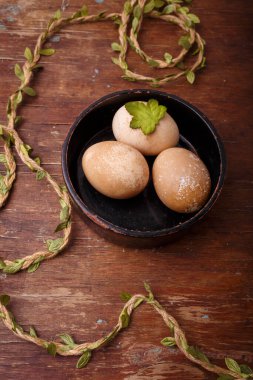 Kırsal arka planda kahverengi Paskalya yumurtaları olan siyah kase. Bahar, Paskalya konsepti. dikey çekim