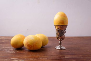 Sarı zerdeçal boyalı Paskalya yumurtası gümüş yumurta kabında, kırsal masada, beyaz arka planda. Mutlu Paskalyalar, bahar konsepti. Boşluğu kopyala