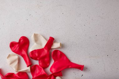 Kırmızı kalp şeklinde yığın beyaz arka planda şişirilmemiş yeni balonlar, üst manzara, kopyalama alanı. Sevgililer günü, düğün, doğum günü dekoru