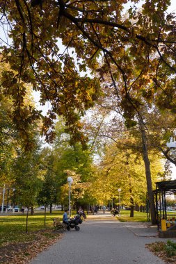 Izmail, Ukraine. September 2021. Beautiful Ukrainian town park, autumn landscape with street lamps, benches and people having rest