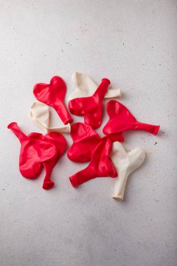 Kırmızı kalp şeklinde yığın beyaz arka planda şişirilmemiş yeni balonlar, üst manzara, kopyalama alanı. Sevgililer günü, düğün, doğum günü dekoru