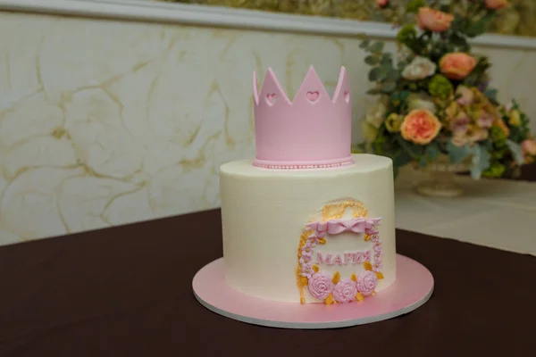 Beautiful girlish birthday cake with pink mastic crown, roses, bow, inscription name Maria. One year old or five years old birthday cake, sweet dessert treat