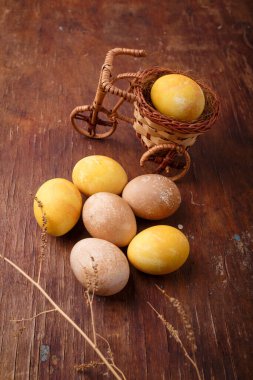 Sarı boyalı Paskalya yumurtası olan kötü oyuncak bisiklet. Kırsal masada kahverengi yumurtalar. Bahar ve Mutlu Paskalyalar konsepti. Dikey çekim