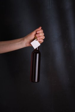 Şablon etiketli kırmızı şarap şişesi, markasız. Siyah arka planda alkollü içecek. Alkol bağımlılığı kavramı