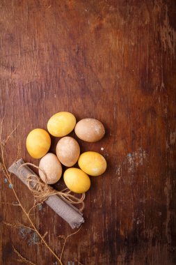 Kahverengi ahşap masada renkli paskalya yumurtaları. Üst görüntü, dikey çekim, kopyalama alanı. Paskalya arkaplanı