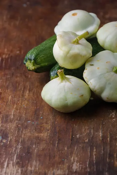 stock image Heap of Patissons, some green pattypan or scallop squashes and zucchini on old brown wooden rustic table background.