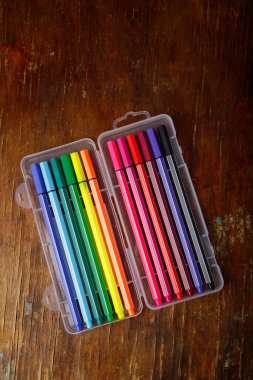Çok renkli keçeli kalemler ya da tahta masa arkasındaki plastik kutuda ince dolma kalemler. Sanat araçları