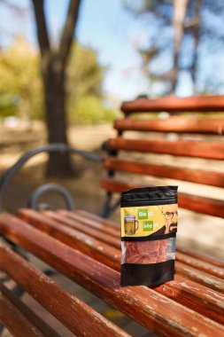 İzmail, Ukrayna. Ekim, 2023. Bir paket kurutulmuş domuz eti, parkta bir bankta kurutulmuş et. Atıştırmalıklar, uygun yiyecekler. Dikey çekim.