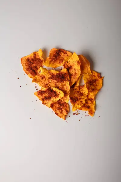 stock image Heap of dried pumpkin slices, dry vegetable crisps, chips pile with pepper and paprika on white background. Advertising banner, copy space. Product presentation. Vertical shot.