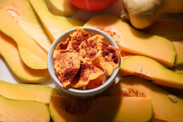 stock image Autumn superfood. Raw and dehydrated crispy pumpkin chips in bowl and white background. Product presentation.