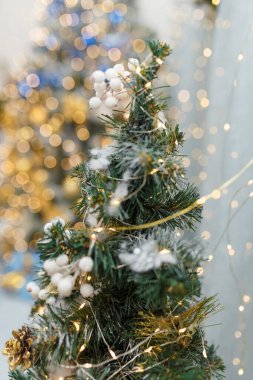 Yapay köknar ağacının tepesinde bulanık altın bokeh arka planda beyaz böğürtlenlerle süslenmiş. Yumuşak odaklı yakın çekim.