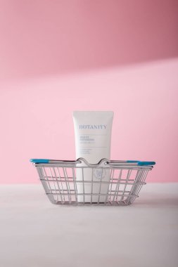 İzmail, Ukrayna. Temmuz 2024. Botanite Aqua uygun güneş esansı SPF 50. Kore kozmetik tüpü pembe arka planda alışveriş sepetinde. Ürün reklam afişi, kopyalama alanı. Beton kemer dekoru. Çevrimiçi sipariş kavramı