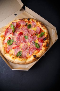 Peynirli, jambonlu, yeşil fesleğenli ve domatesli pizza. Gıda ürünleri reklam afişi, kopyalama alanı.