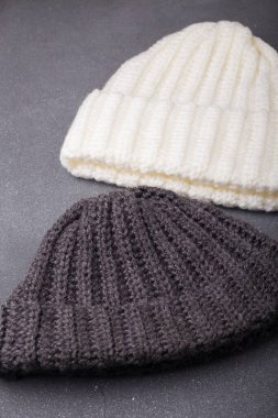 İki örülmüş yün bere ya da şapka, beyaz ve gri ahşap arka planda, düz yatıyordu.