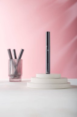 İzmail, Ukrayna. 16 Ağustos 2024. Missha 3D göz, maskara tüpünü beyaz beton dekorda, pembe arka planda kirletir. Camdaki bazı tüpleri. Boşluğu kopyala.