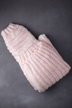 Yünlü açık pembe süveter, gri arka planda katlanmış örgü kazak, üst manzara. Boşluğu kopyala