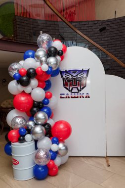 İzmail, Ukrayna. Temmuz 2024. Erkek doğum günü partisi için çok renkli balonlar. Beyaz arkaplanda Transformers logosu olan fotoğraf bölgesi.