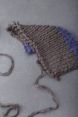 Gri arka planda örülmüş saç örgüsü ve akrilik giysinin bir parçası. Örgü ipliği. 