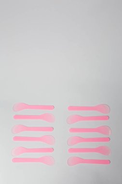 Balmumu depilasyonu ya da beyaz arka planda şekerleme için birkaç adet tek kullanımlık pembe plastik spatula. Güzellik prosedürleri, cilt bakımı. Boşluğu kopyala.