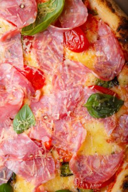 Pizza yakın çekim dokusu, yemek kalıbı geçmişi. Jambon, domates, yeşil fesleğen yaprağı ve peynir. Üst görünüm.