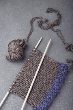 Gri arka planda örgü ören kumaşlar, saç örgüsü ve akrilik iplik topları..