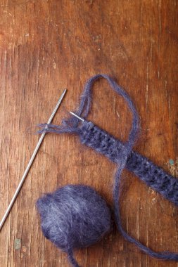 Eski ahşap arka planda örgü iğneleri ve koyu mavi yün yumağı. Örgü örmeye başlıyorum.