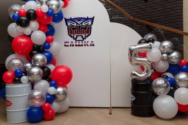 İzmail, Ukrayna. 21 Temmuz 2024. 5 yıllık erkek doğum günü partisi için çok renkli balonlar. Beyaz arka planda Transformers logosu olan fotoğraf bölgesi. Yazı - Sashka (isim)