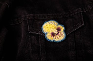 Yumuşak, kalp kaplaması nakış işlemeli siyah kot pantolon kumaş arka planda boncuklar, yakın çekim, uzay kopyalama.