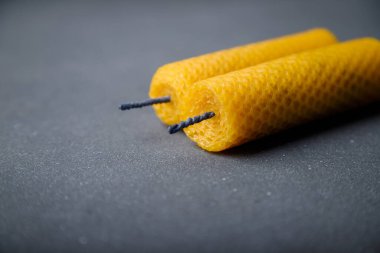 Gri ahşap arka planda doğal arı cilasından yapılmış iki sarı desenli mum, boşluğu kopyala.