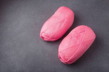 Gri arka planda örgü örmek ya da örmek için iki tane parlak pembe akrilik iplik. Düz yat, boşluğu kopyala.