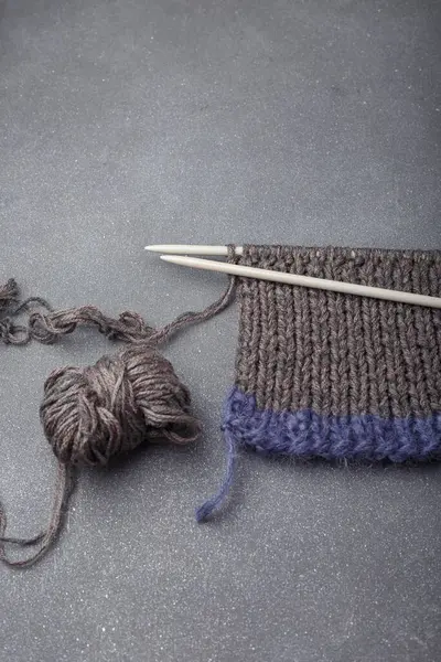 Gri arka planda örgü ören kumaşlar, saç örgüsü ve akrilik iplik topları..